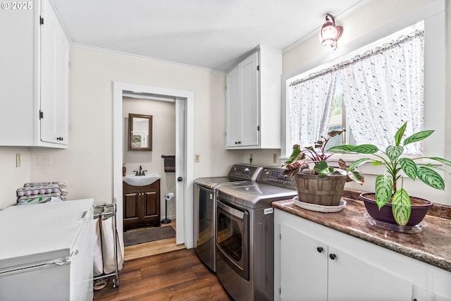 laundry area with washing machine and clothes dryer, cabinet space, dark wood-style flooring, and ornamental molding