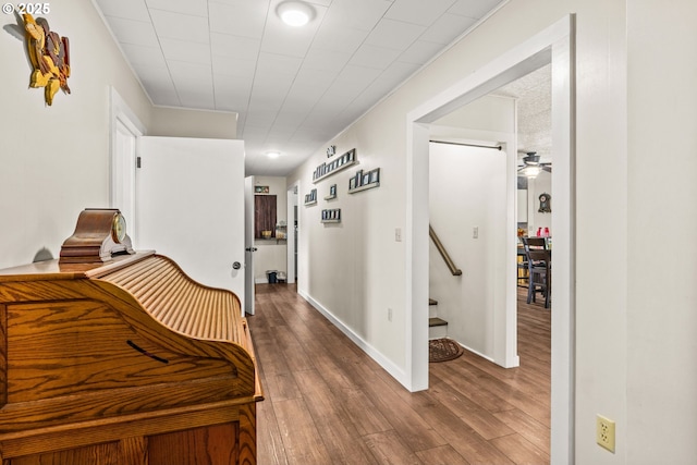 hall with wood finished floors, stairway, and baseboards
