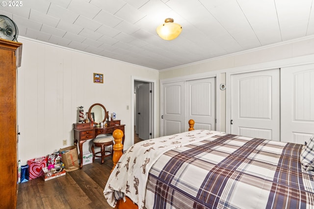 bedroom with dark wood-type flooring, multiple closets, and ornamental molding