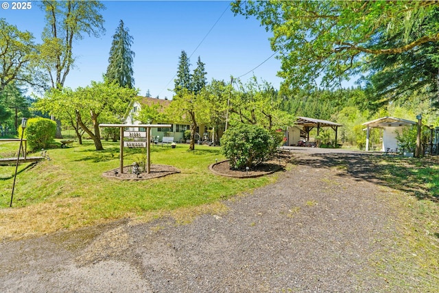 surrounding community featuring a detached carport, a yard, and driveway