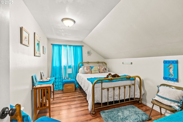 bedroom featuring wood finished floors, lofted ceiling, and baseboards