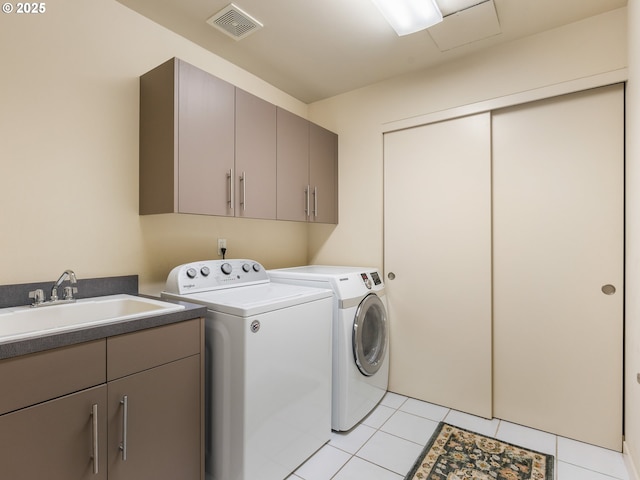 clothes washing area featuring sink, cabinets, washer and clothes dryer, and light tile patterned floors