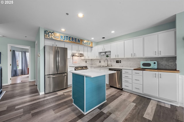 kitchen with a sink, stainless steel appliances, tasteful backsplash, and dark wood-type flooring