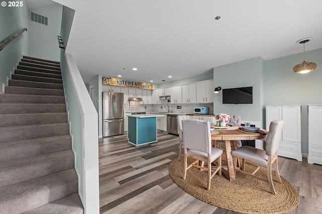 dining space featuring recessed lighting, visible vents, wood finished floors, and stairway