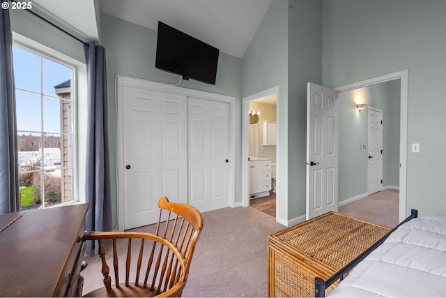 carpeted bedroom with ensuite bath, baseboards, a closet, and high vaulted ceiling