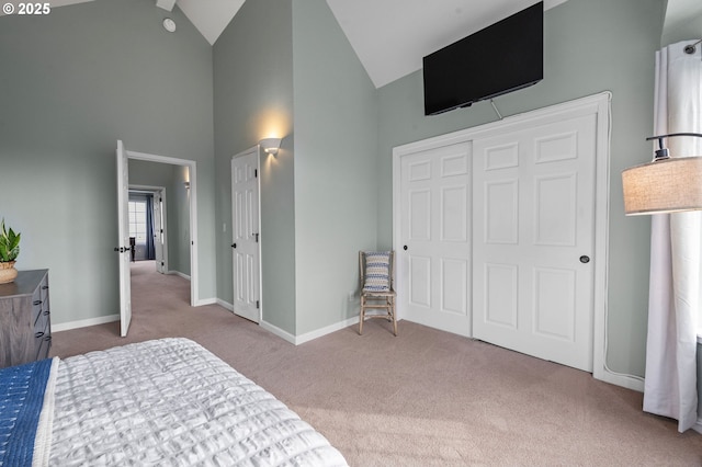 carpeted bedroom featuring a closet, high vaulted ceiling, and baseboards