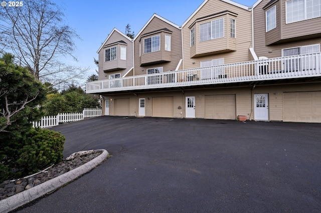 view of property featuring driveway, an attached garage, and fence