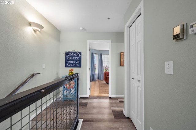 hallway with an upstairs landing, wood finished floors, and baseboards