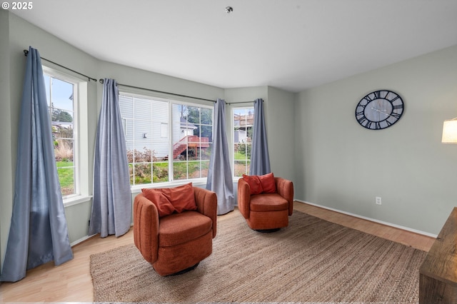 living area featuring light wood finished floors, baseboards, and a wealth of natural light