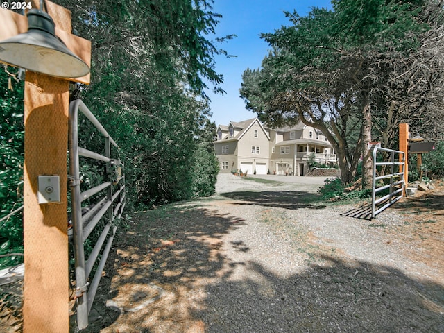 view of road with gravel driveway, a gate, a residential view, and a gated entry