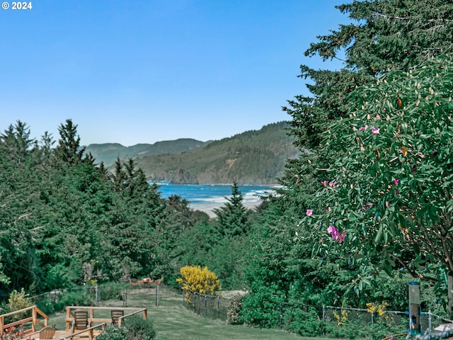 view of water feature with a forest view, a mountain view, and fence