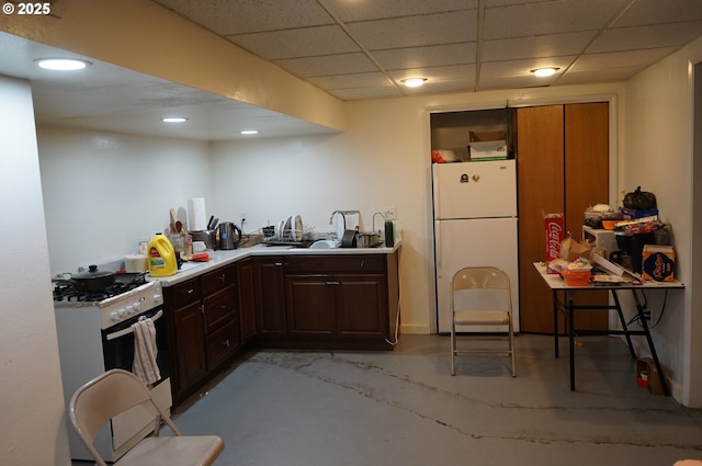 kitchen featuring white refrigerator, dark brown cabinets, a drop ceiling, and range with gas cooktop