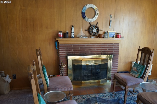 sitting room featuring dark tile patterned flooring, wooden walls, and a fireplace