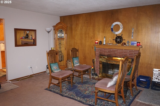 sitting room featuring carpet, a textured ceiling, a fireplace, and wood walls