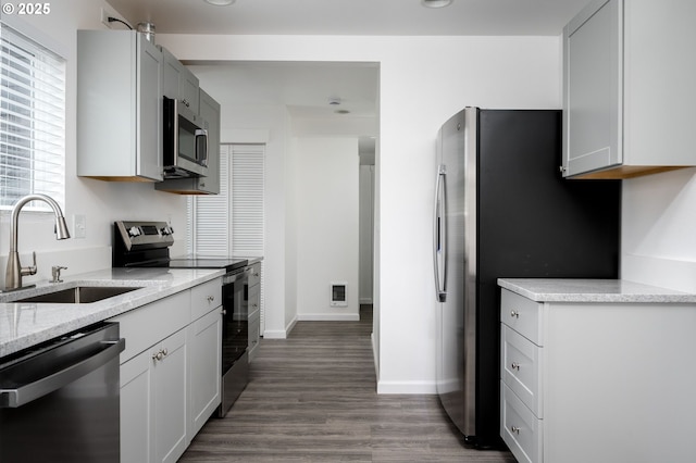 kitchen with sink, white cabinets, hardwood / wood-style flooring, light stone counters, and stainless steel appliances