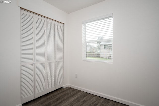 unfurnished bedroom with dark hardwood / wood-style flooring and a closet