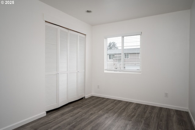 unfurnished bedroom featuring dark hardwood / wood-style flooring and a closet