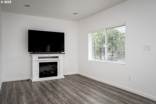 unfurnished living room with dark wood-type flooring and a premium fireplace