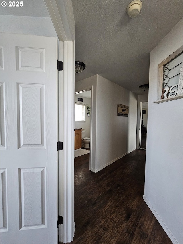 corridor with a textured ceiling and dark hardwood / wood-style floors