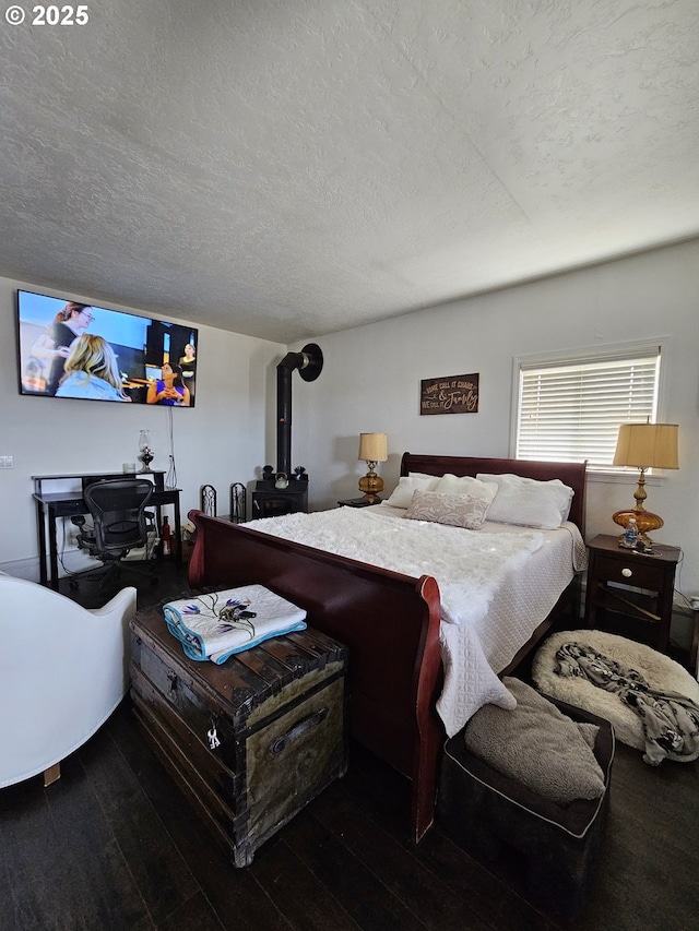 bedroom with a textured ceiling, a wood stove, and dark hardwood / wood-style floors