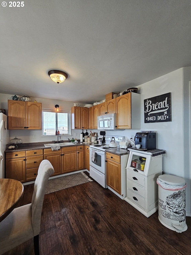 kitchen featuring sink, white appliances, a textured ceiling, and dark hardwood / wood-style floors