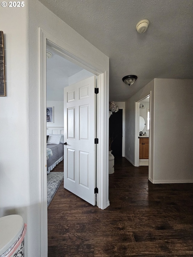 hall featuring a textured ceiling and dark wood-type flooring