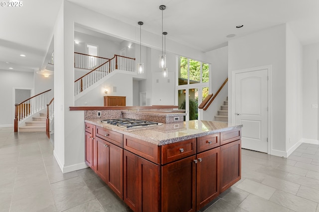 370 NW 81st Pl, Portland, OR 97229 - kitchen with stainless steel gas stovetop, baseboards, light stone countertops, decorative light fixtures, and reddish brown cabinets