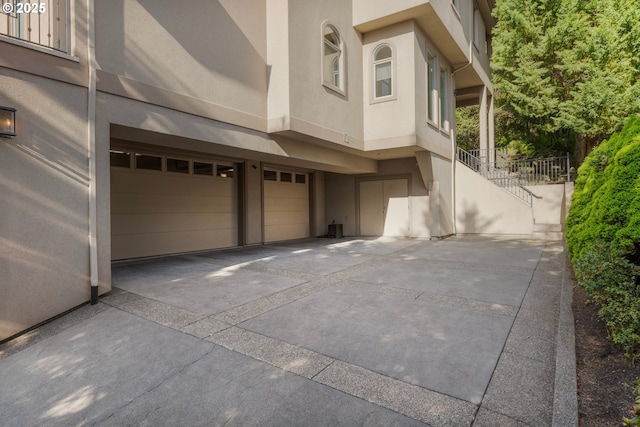 370 NW 81st Pl, Portland, OR 97229 - view of side of home featuring stucco siding, an attached garage, stairs, and concrete driveway
