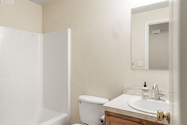 full bathroom with toilet, shower / tub combination, vanity, and a textured wall