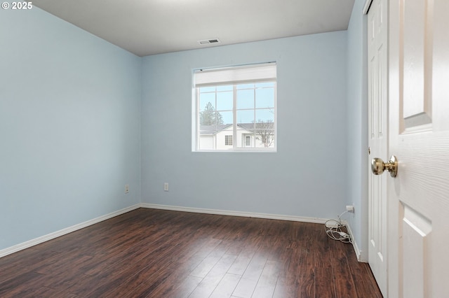 spare room featuring visible vents, baseboards, and dark wood-style flooring