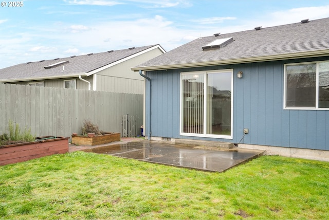 back of property with a patio, fence, roof with shingles, a vegetable garden, and a lawn