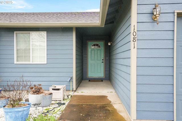 doorway to property featuring roof with shingles