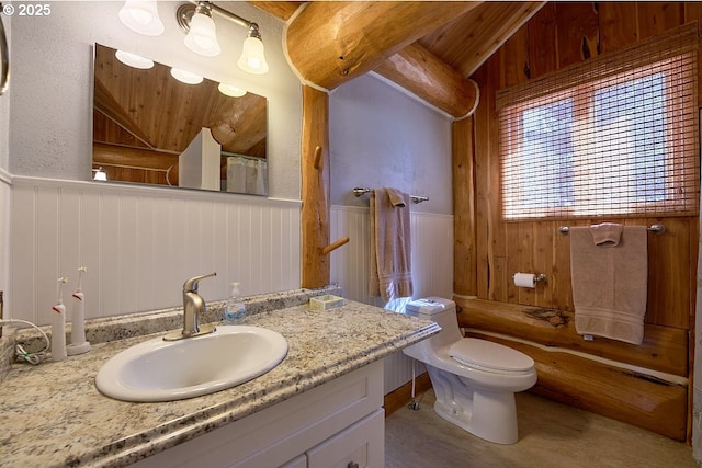 bathroom featuring toilet, wood walls, vanity, curtained shower, and wainscoting