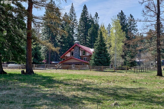 view of yard with a forest view and fence