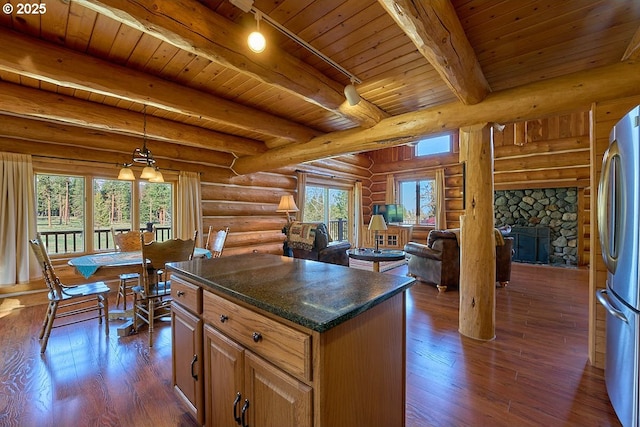 kitchen with beam ceiling, freestanding refrigerator, open floor plan, a center island, and dark wood-style floors