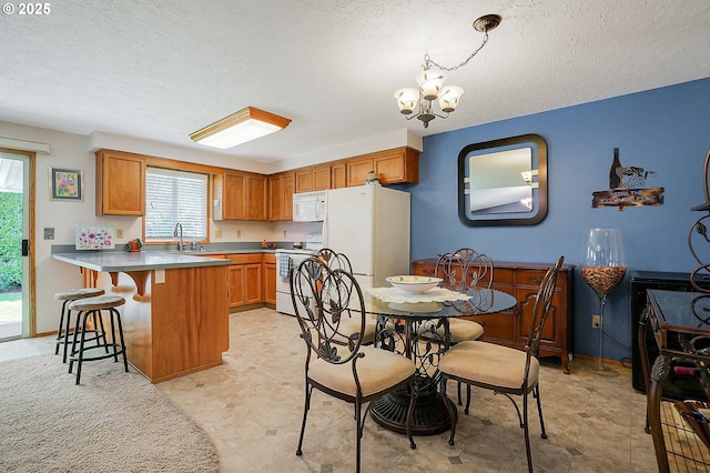 5219 Lacey Ct N, Keizer, OR 97303 - kitchen featuring a peninsula, white appliances, an inviting chandelier, and a textured ceiling