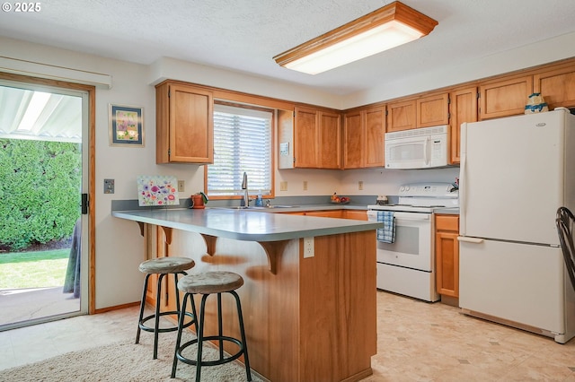 5219 Lacey Ct N, Keizer, OR 97303 - kitchen featuring a peninsula, a kitchen breakfast bar, a sink, white appliances, and brown cabinets