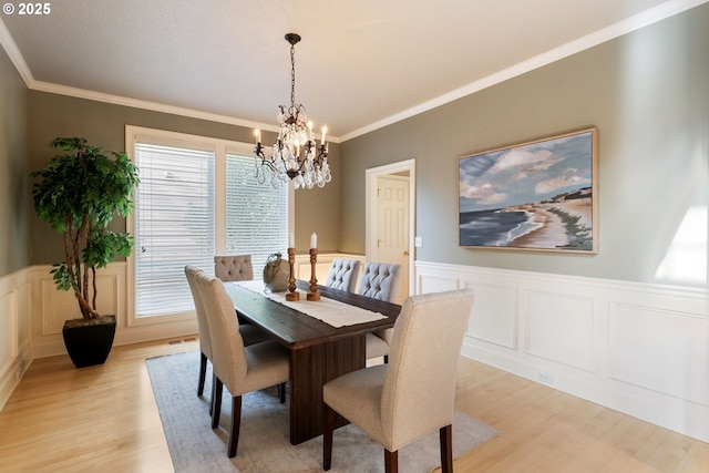 13581 SW Essex Dr, Portland, OR 97223 - dining area with light wood-type flooring, a chandelier, wainscoting, crown molding, and a decorative wall