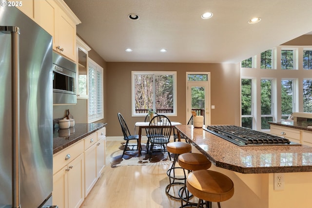 13581 SW Essex Dr, Portland, OR 97223 - kitchen with stainless steel appliances, recessed lighting, light wood-style floors, a kitchen island, and a kitchen breakfast bar