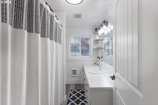 full bathroom featuring visible vents, wood finished floors, baseboards, a heating unit, and vanity