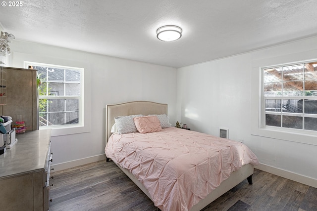 bedroom featuring a textured ceiling, baseboards, and wood finished floors