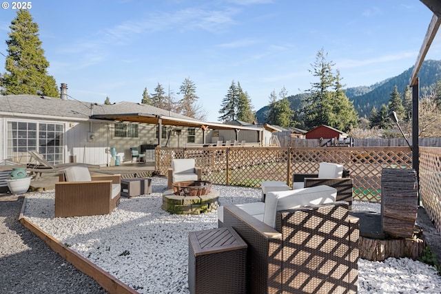 view of patio / terrace featuring fence, a mountain view, and an outdoor fire pit