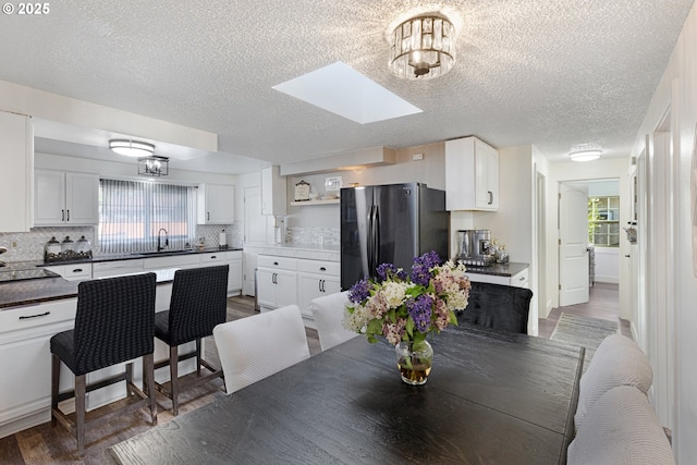 dining area featuring light wood finished floors, a textured ceiling, and a skylight