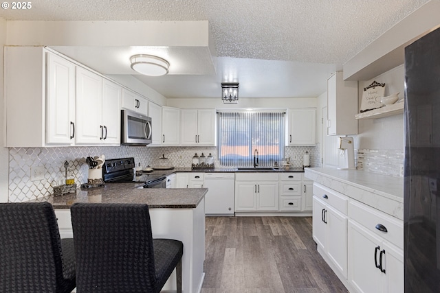 kitchen with stainless steel microwave, open shelves, white dishwasher, black electric range oven, and a sink