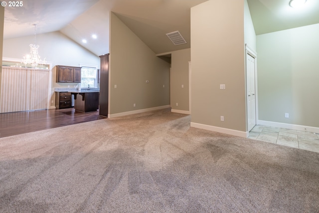 unfurnished living room featuring high vaulted ceiling, visible vents, light colored carpet, a sink, and a chandelier