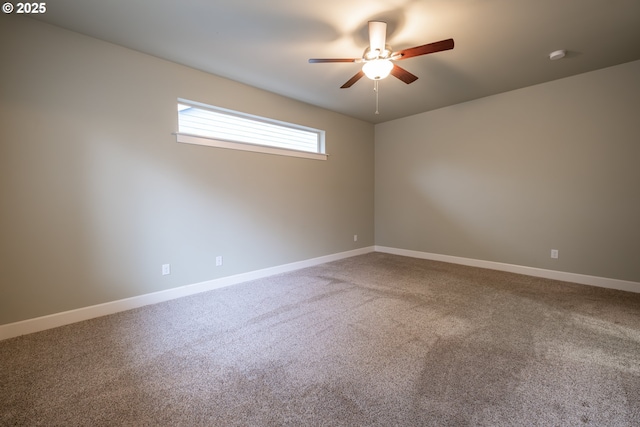 carpeted spare room with a ceiling fan and baseboards