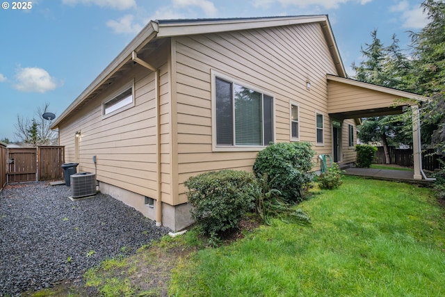 view of side of home with central AC, a yard, fence, and a gate