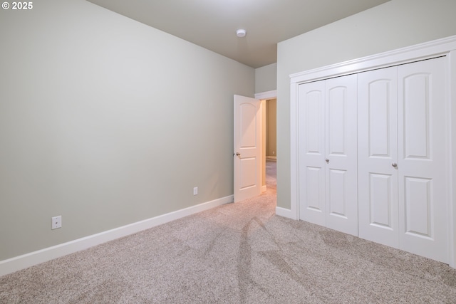 unfurnished bedroom featuring carpet floors, baseboards, and a closet