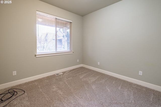 carpeted spare room with visible vents and baseboards