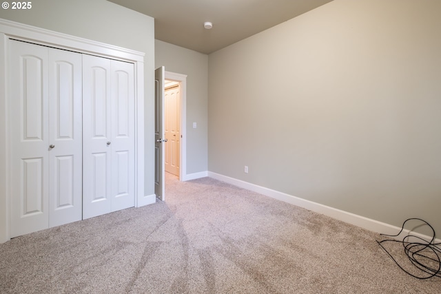 unfurnished bedroom featuring carpet floors, a closet, and baseboards